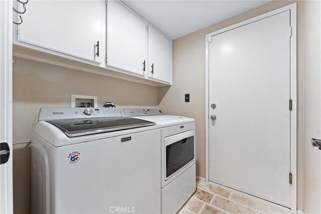 laundry room featuring separate washer and dryer, cabinet space, and stone finish floor