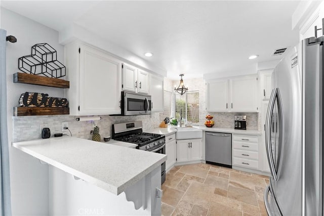 kitchen with stainless steel appliances, a peninsula, light countertops, and white cabinetry