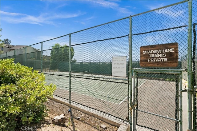 view of tennis court featuring a gate and fence