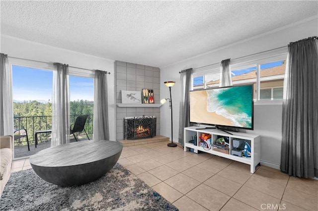 living room with a textured ceiling, tile patterned flooring, a large fireplace, and a healthy amount of sunlight