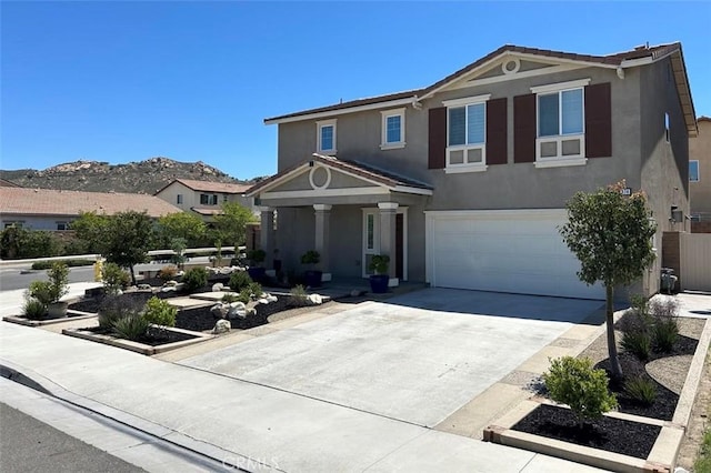 5374 Mission Rock Way, Jurupa Valley, CA 92509 - traditional-style home with a mountain view, driveway, covered porch, an attached garage, and stucco siding