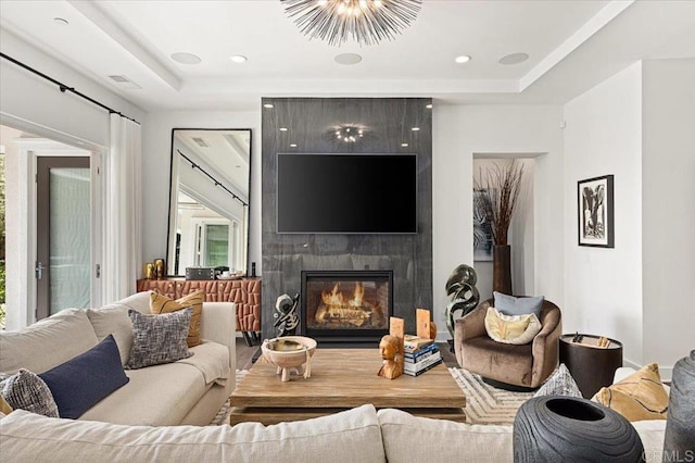 living room featuring recessed lighting, a tray ceiling, visible vents, and a fireplace