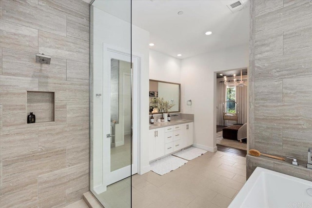 ensuite bathroom with connected bathroom, vanity, a soaking tub, a tile shower, and visible vents