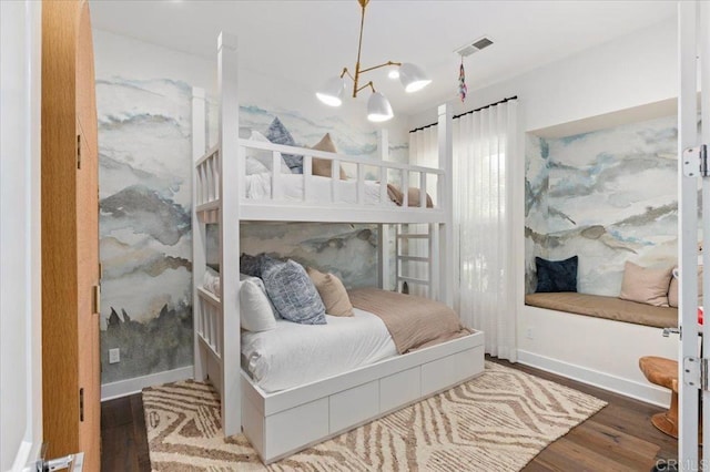 bedroom with baseboards, a chandelier, wood finished floors, and visible vents