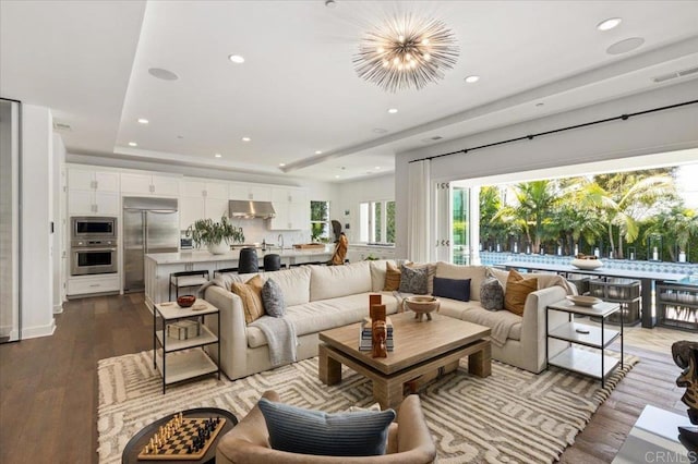 living area with recessed lighting, visible vents, dark wood-style flooring, and a tray ceiling