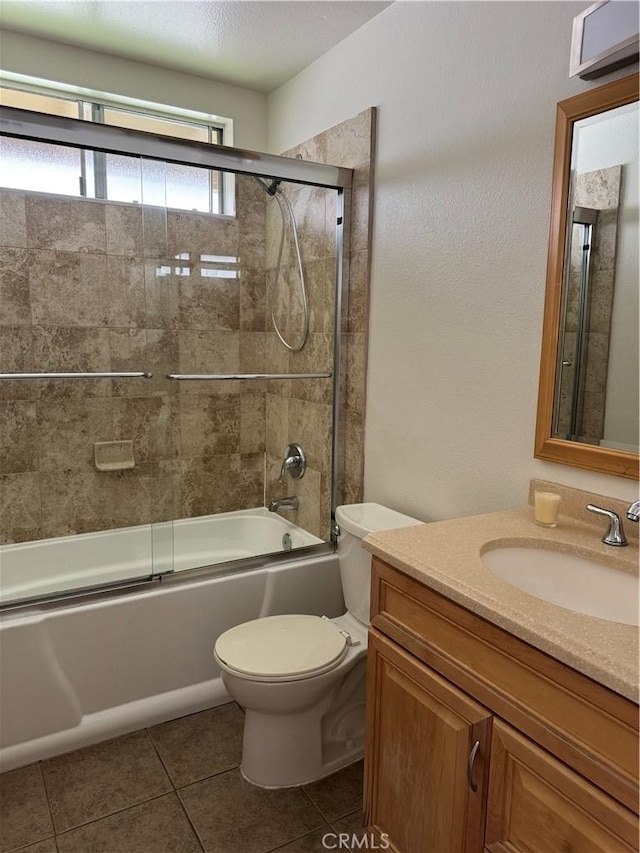 bathroom featuring toilet, tile patterned floors, vanity, and enclosed tub / shower combo