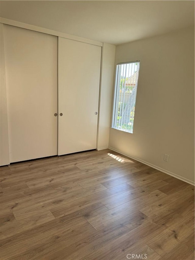 unfurnished bedroom with a closet, baseboards, and wood finished floors