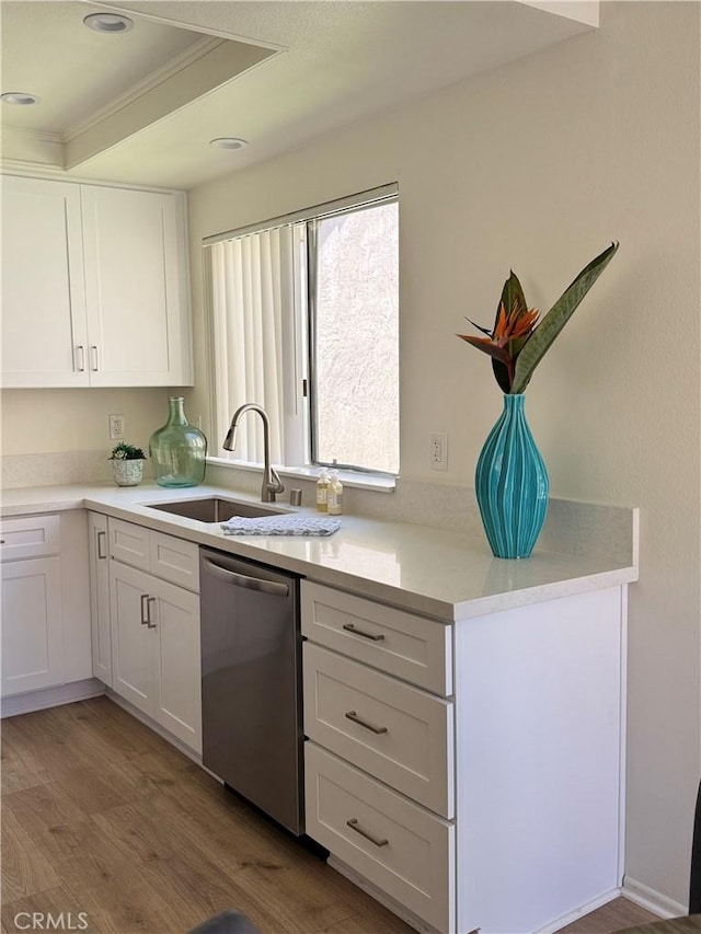 kitchen featuring a sink, light wood-style flooring, light countertops, white cabinets, and stainless steel dishwasher