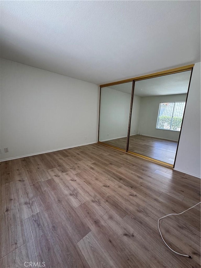 unfurnished bedroom with a textured ceiling, a closet, and wood finished floors