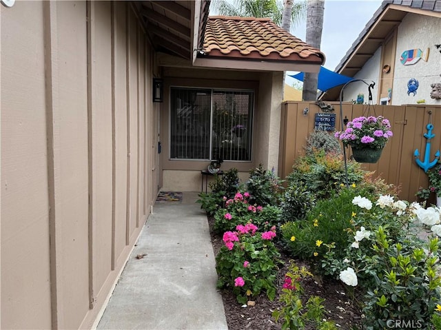 property entrance featuring stucco siding, fence, and a tiled roof