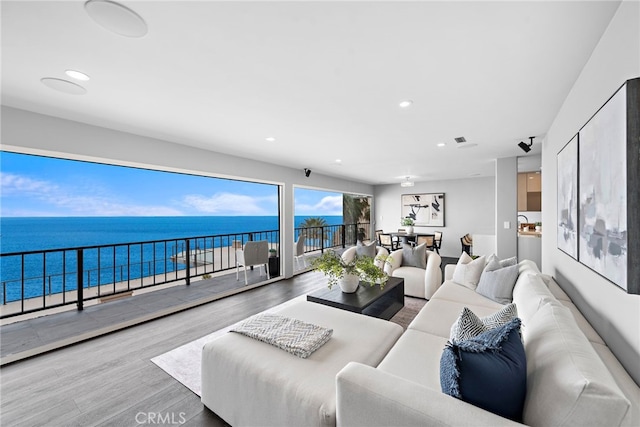 living room featuring wood finished floors, recessed lighting, visible vents, and a water view