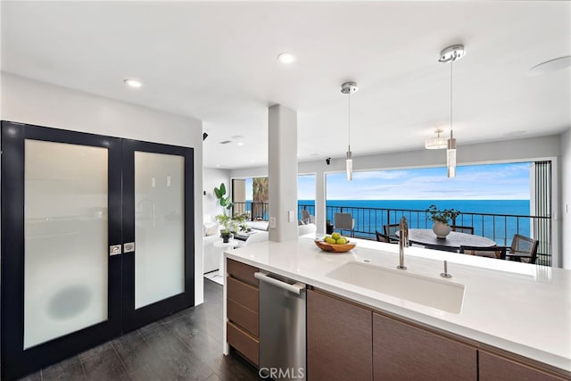 kitchen with stainless steel dishwasher, a sink, light countertops, french doors, and hanging light fixtures