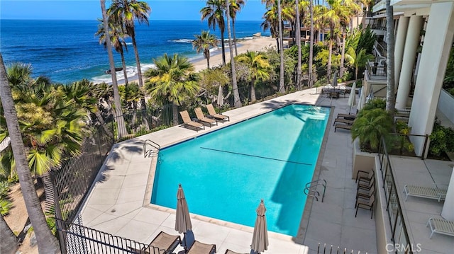 pool with fence, a beach view, a water view, and a patio