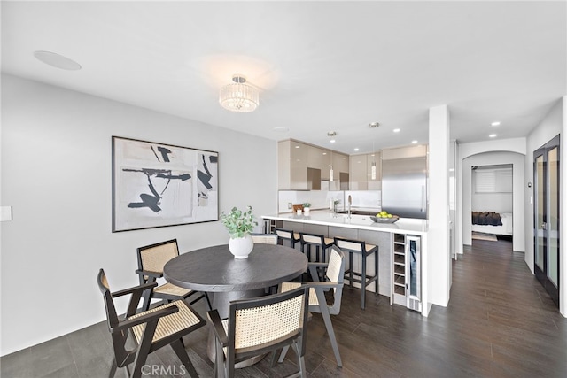 dining space with dark wood-style flooring, wine cooler, recessed lighting, and a notable chandelier