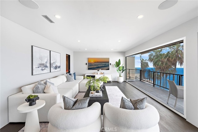living area featuring wood finished floors, visible vents, recessed lighting, and a water view
