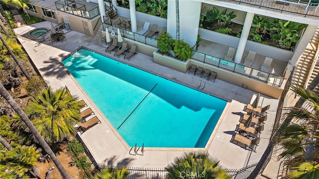 pool with fence, a patio area, and a hot tub