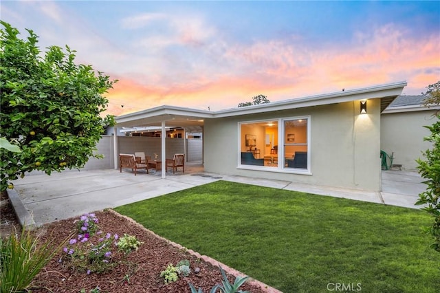 347 E Barkley Ave, Orange, CA 92867 - back of house at dusk featuring stucco siding, a lawn, and a patio