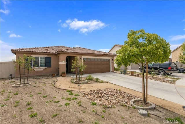 view of front of home with driveway, fence, a tiled roof, stucco siding, and a garage