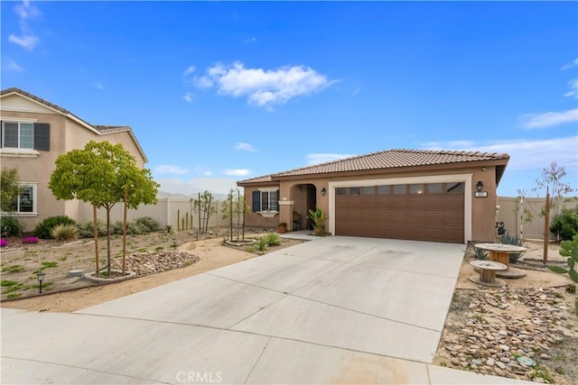 view of front facade featuring stucco siding, fence, a tile roof, concrete driveway, and an attached garage