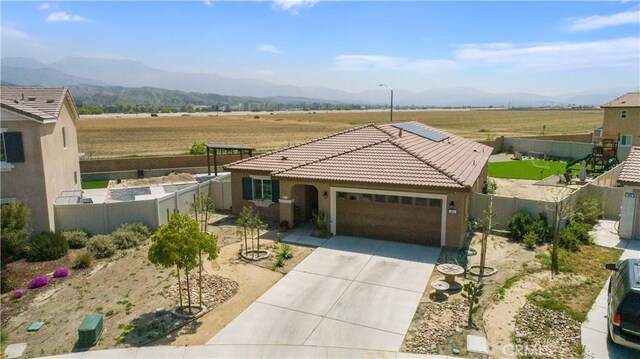 single story home with a mountain view, driveway, a garage, and fence