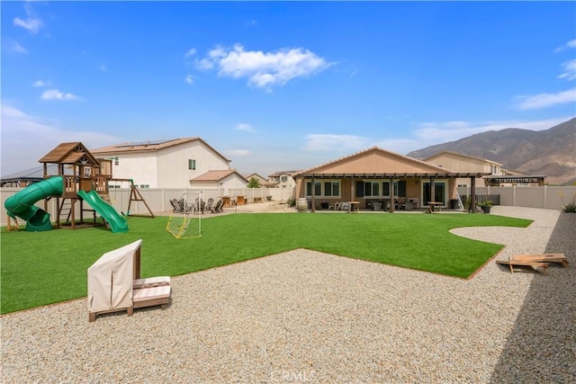 rear view of property featuring a lawn, a fenced backyard, a playground, and a patio area