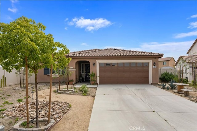 mediterranean / spanish house featuring stucco siding, concrete driveway, a tile roof, and a garage