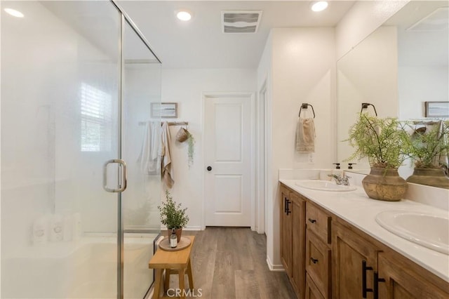 full bath with wood finished floors, visible vents, a stall shower, and a sink