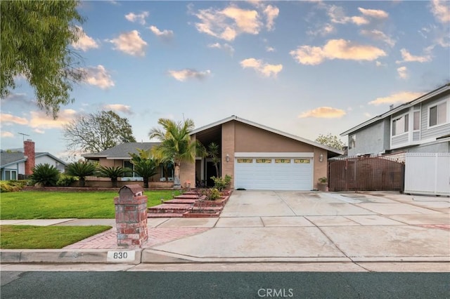 mid-century home featuring a front lawn, driveway, an attached garage, fence, and stucco siding