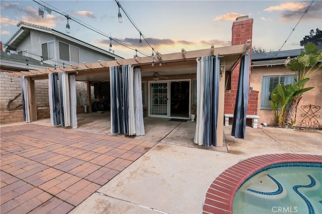 back of house at dusk featuring a pergola, a chimney, an outdoor pool, a patio, and ceiling fan