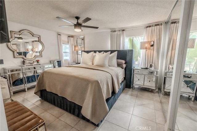 bedroom with a textured ceiling, ceiling fan, and light tile patterned flooring