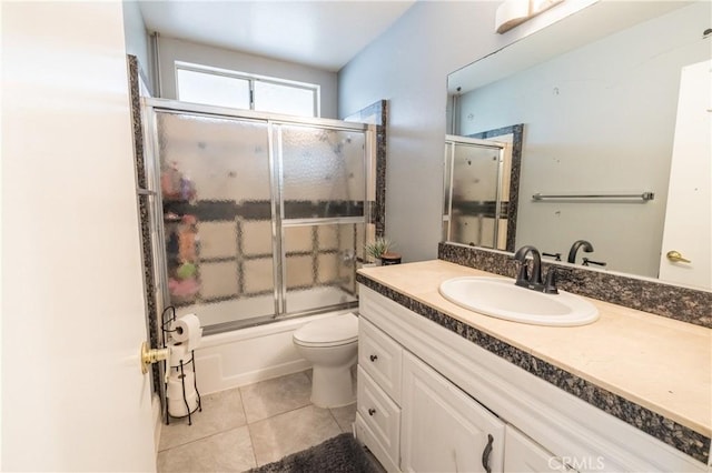 full bathroom featuring vanity, tile patterned floors, bath / shower combo with glass door, and toilet