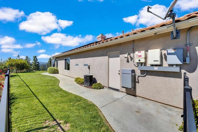 view of home's exterior featuring stucco siding, a yard, and a chimney