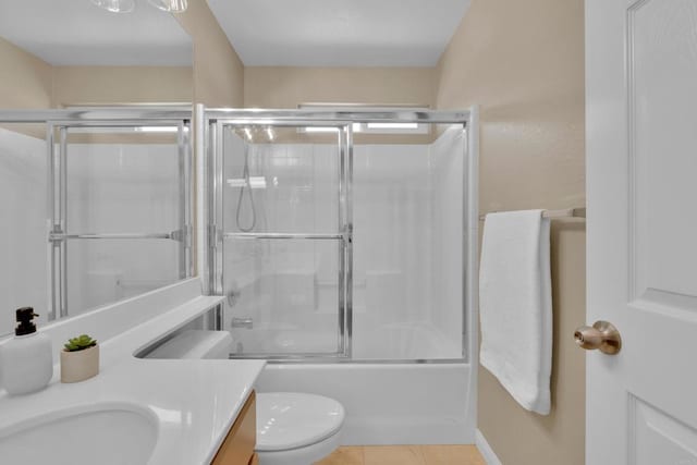bathroom featuring vanity, tile patterned flooring, bath / shower combo with glass door, and toilet