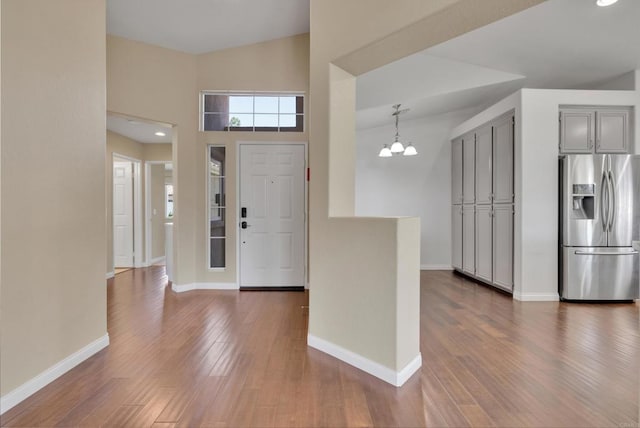 foyer with baseboards, dark wood-style flooring, a towering ceiling, and a chandelier