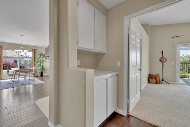 clothes washing area with dark wood-style flooring, baseboards, and a notable chandelier