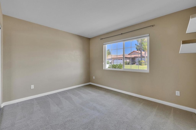 spare room featuring carpet floors and baseboards