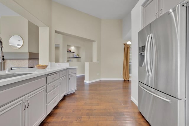 kitchen featuring dark wood-style flooring, baseboards, stainless steel refrigerator with ice dispenser, light countertops, and white cabinets