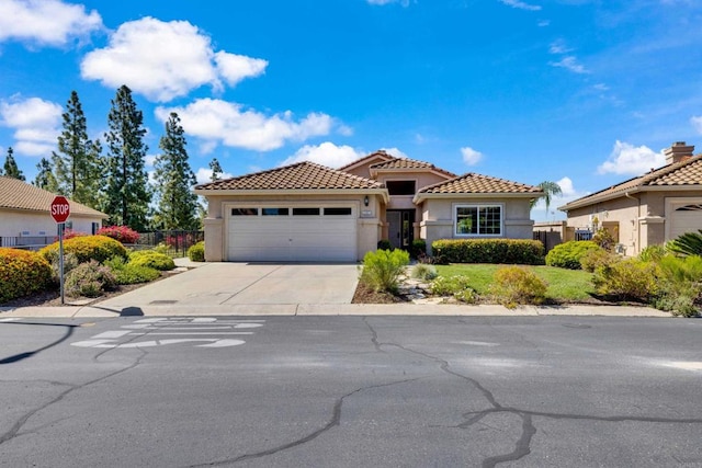 mediterranean / spanish home featuring fence, stucco siding, concrete driveway, and a garage
