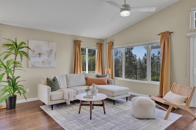 living area with baseboards, a ceiling fan, vaulted ceiling, and wood finished floors