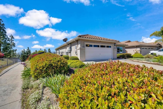view of home's exterior with fence, an attached garage, driveway, and stucco siding