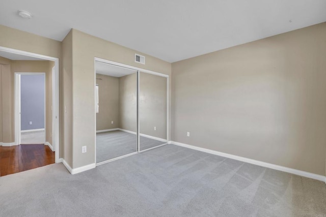 unfurnished bedroom featuring visible vents, carpet flooring, baseboards, and a closet