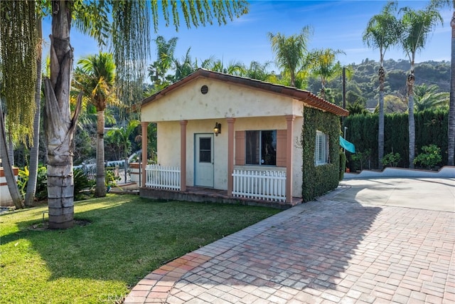 bungalow-style home with a porch, driveway, a front yard, and stucco siding
