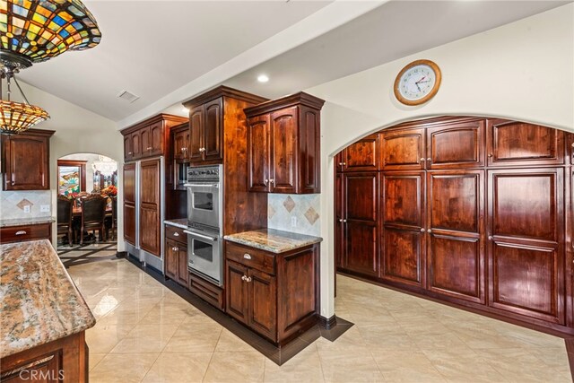 kitchen featuring backsplash, arched walkways, light stone counters, and stainless steel double oven
