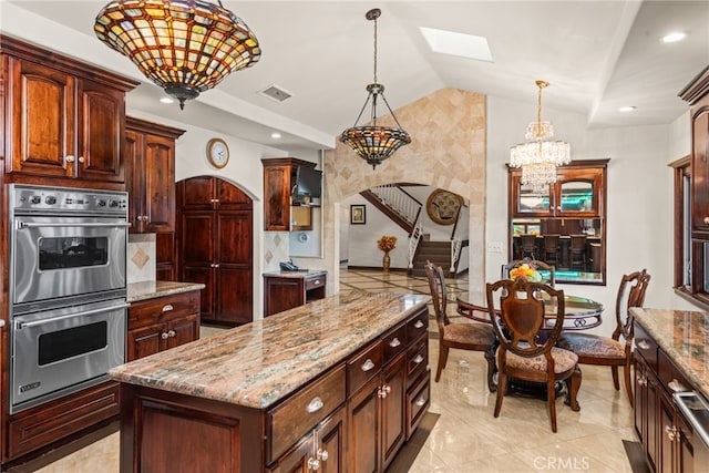 kitchen featuring a center island, vaulted ceiling with skylight, stainless steel double oven, an inviting chandelier, and visible vents