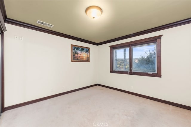 unfurnished room featuring visible vents, baseboards, ornamental molding, and light colored carpet