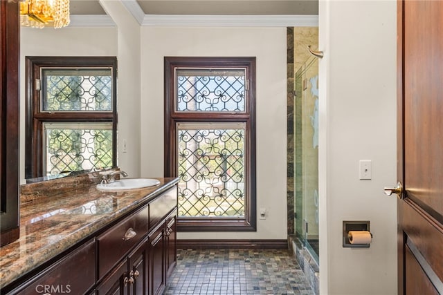 bathroom with a chandelier, vanity, baseboards, and a wealth of natural light