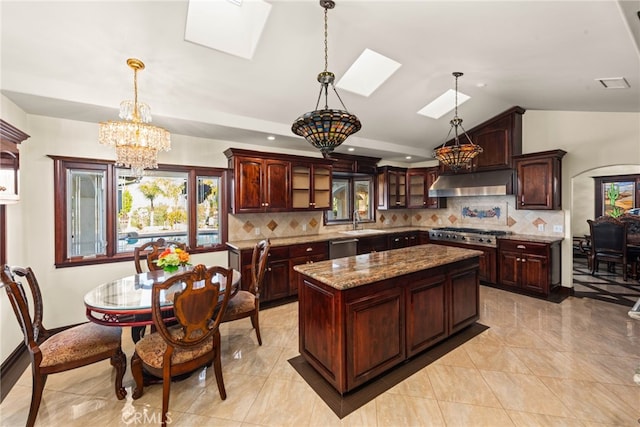 kitchen featuring a sink, decorative backsplash, an inviting chandelier, under cabinet range hood, and a kitchen island