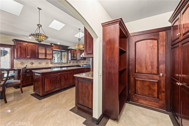 kitchen featuring glass insert cabinets, light stone countertops, a center island, decorative backsplash, and hanging light fixtures