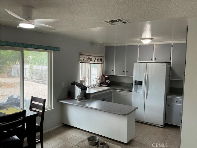 26221 Germantown Dr, Menifee, CA 92586 - kitchen featuring white appliances, a sink, light tile patterned floors, a peninsula, and a textured ceiling
