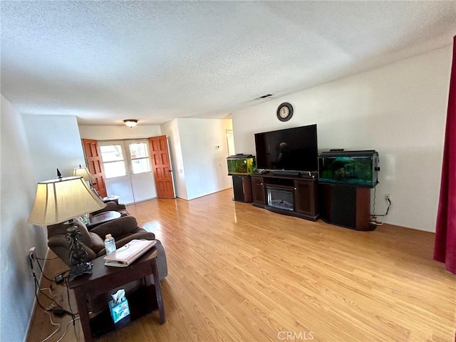 26221 Germantown Dr, Menifee, CA 92586 - living room with light wood finished floors, a textured ceiling, and french doors
